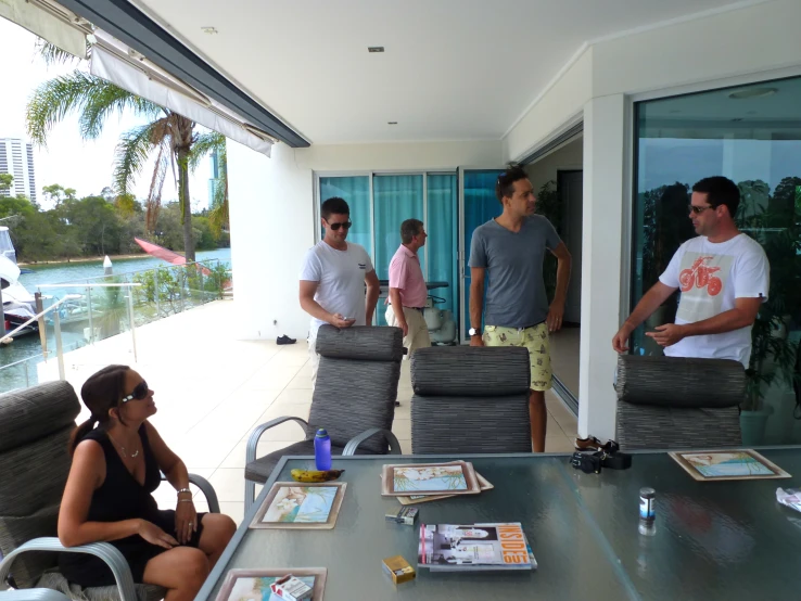 four people sitting and standing around looking at some water