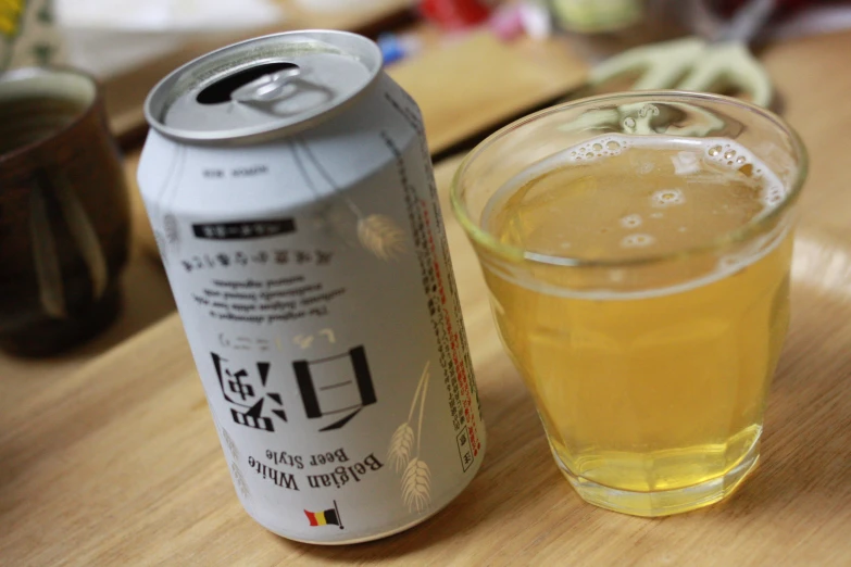 a glass cup on a table next to a can of beer