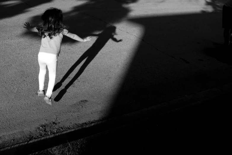 a little girl standing on the street with her hands extended