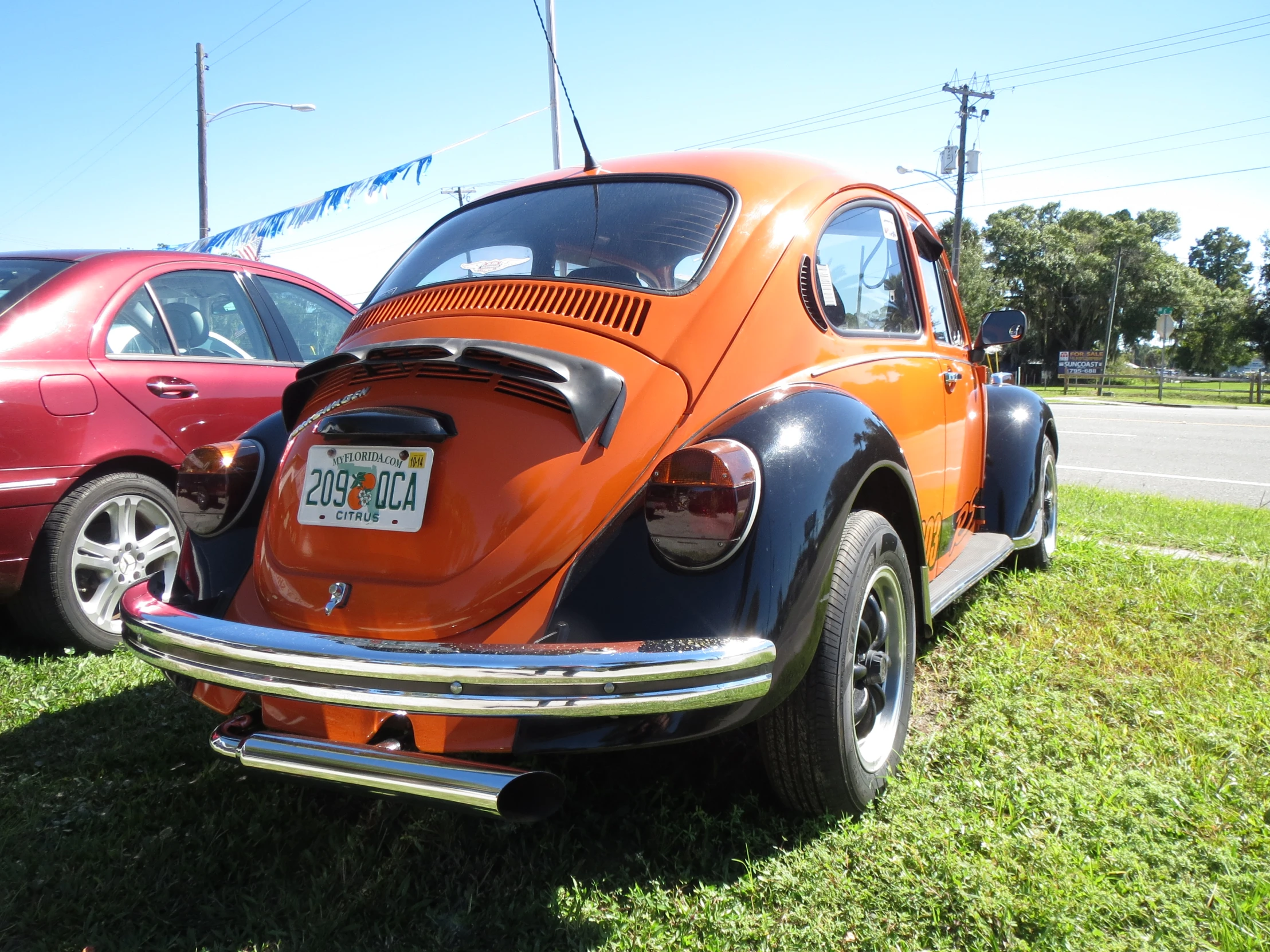 an orange car sitting next to a red car on the grass