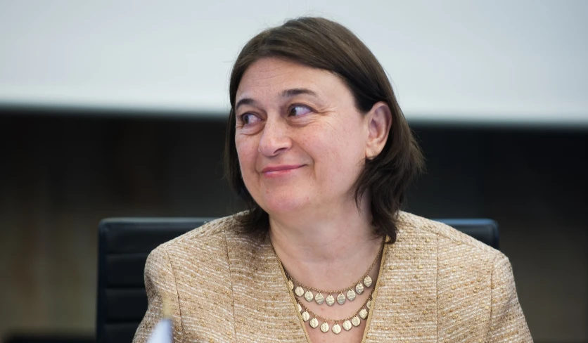 a lady wearing an eye ring with a brown blazer on and a white blouse