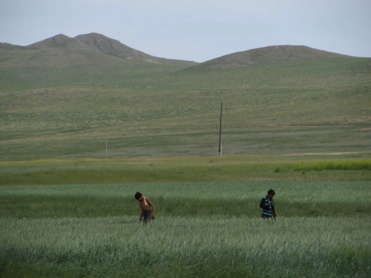 two people in a large open field next to a mountain