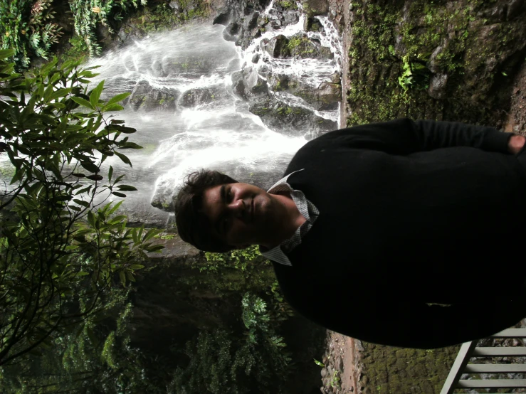 there is a man standing by a waterfall looking at the camera