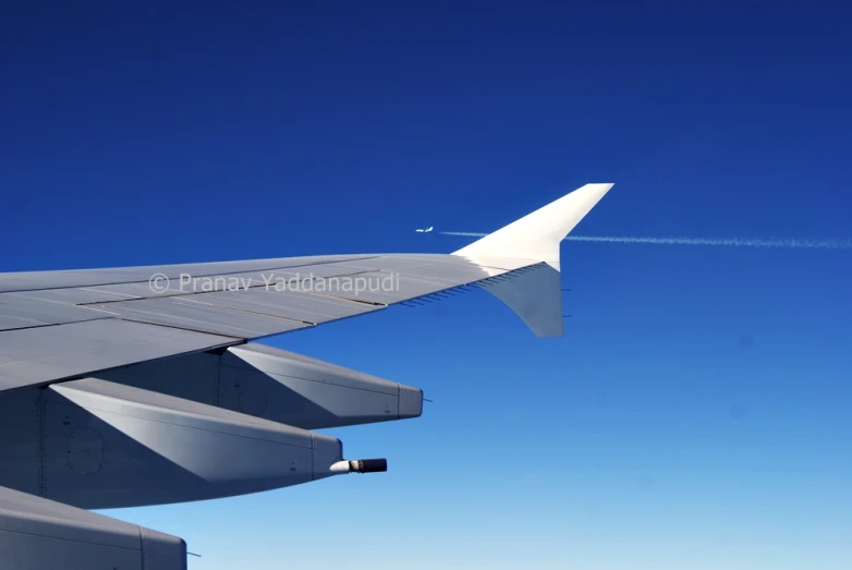 an airplane wing flying through a bright blue sky