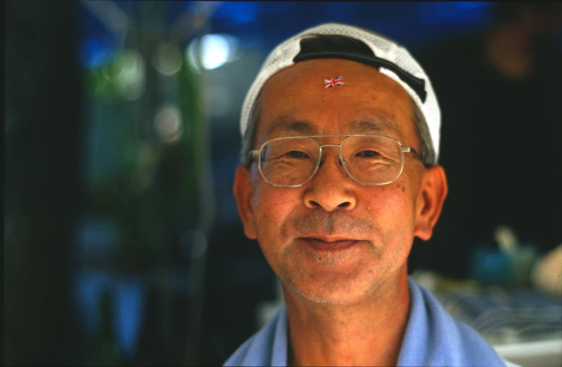an old asian man wearing glasses and a headscarf