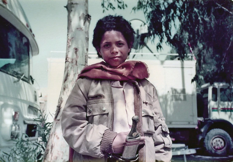 a woman wearing a scarf and jacket posing in front of an rv