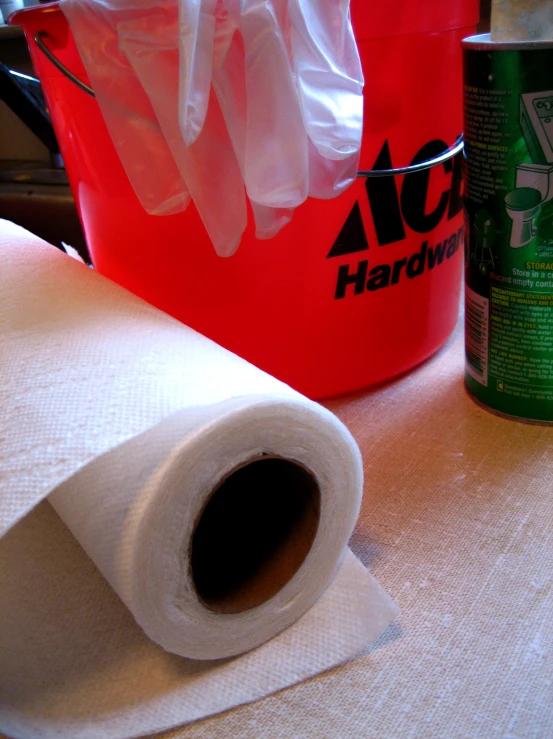 a container with some cleaning supplies and a roll of tissue