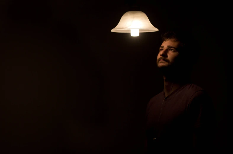 a man stares up from underneath a light