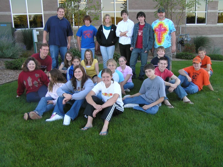 a group of people standing and sitting on top of a green grass covered field