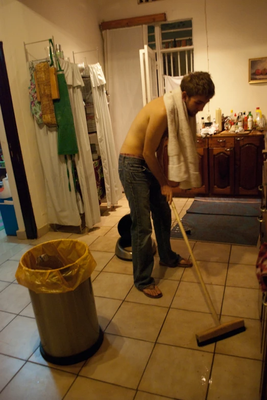 a man cleaning a kitchen floor with a mop