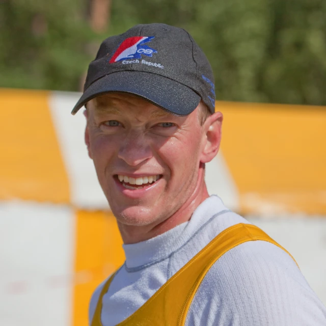 a man is smiling wearing a cap