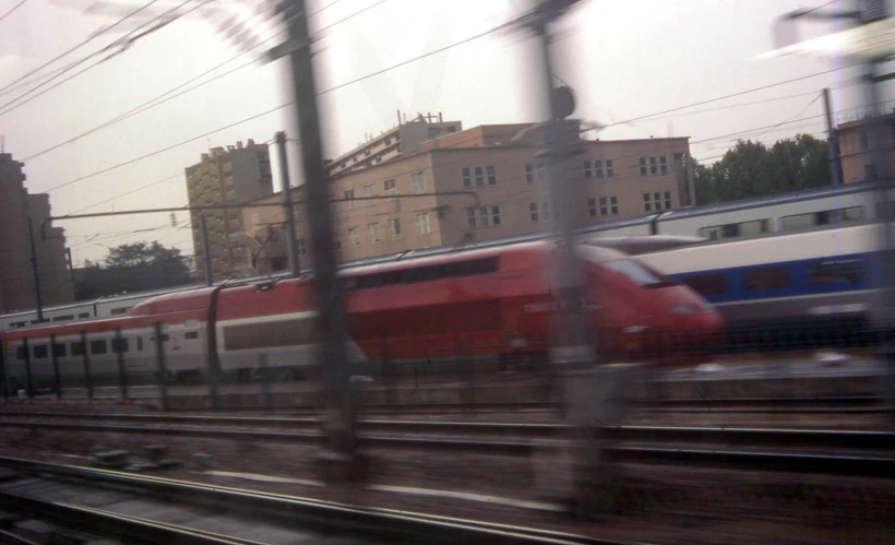 two trains on the tracks, with old buildings in the background