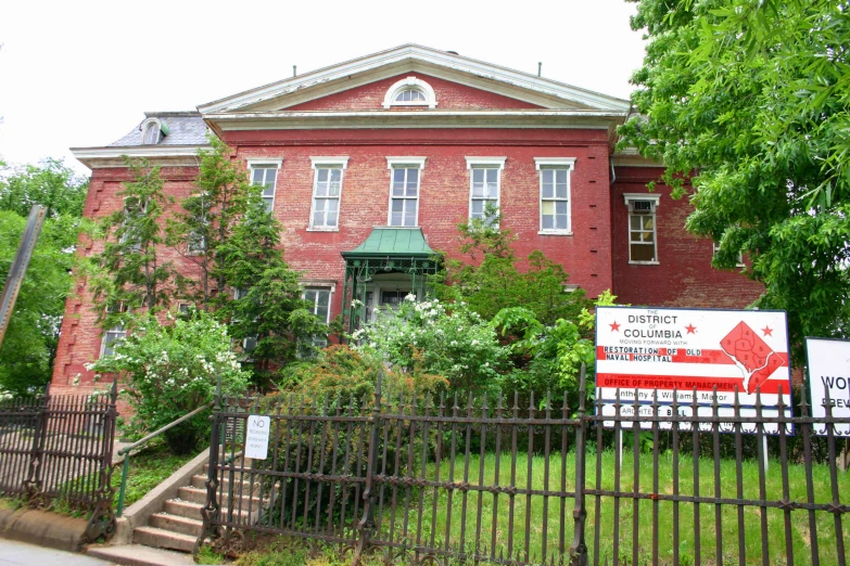 a large red brick building with trees and fence around it