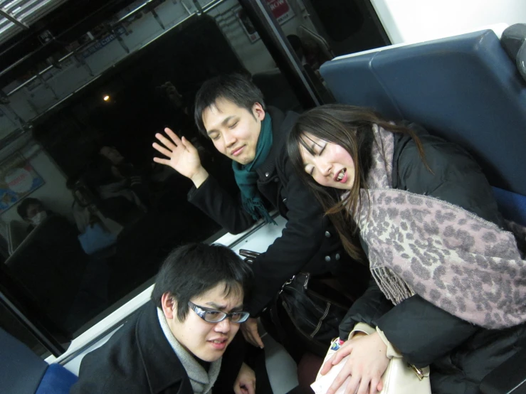 three people riding on a train looking up at soing