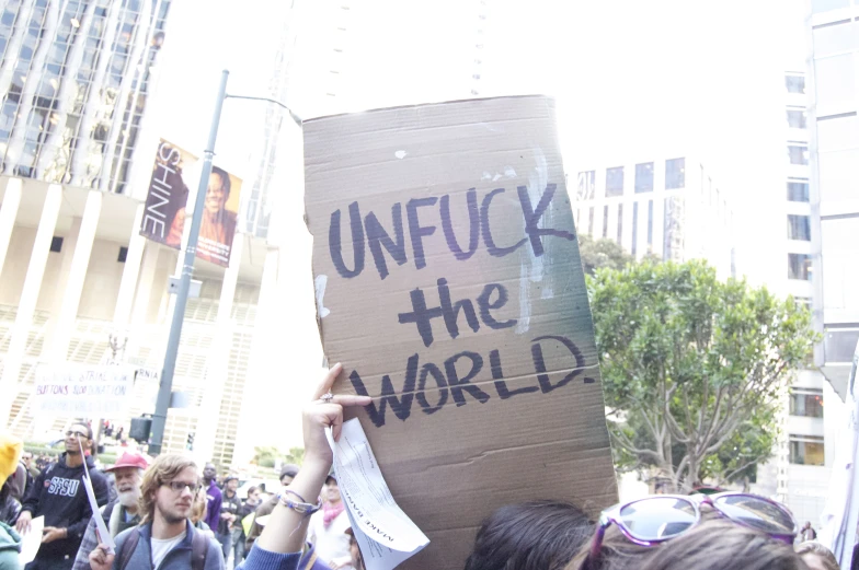 a protester holds up a cardboard sign in a crowd