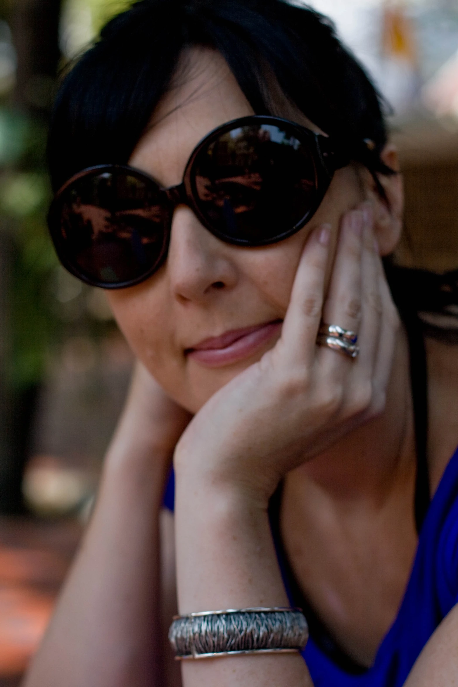 a woman is smiling while wearing big round sunglasses