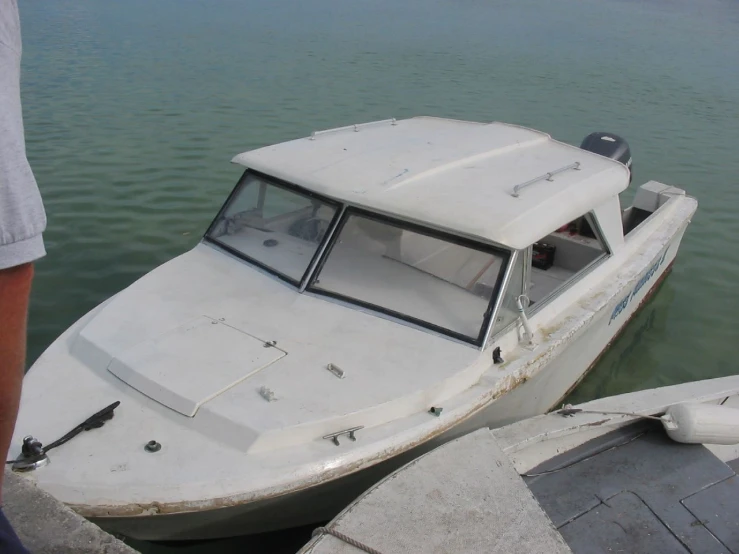 a small boat in the water sitting next to some docks