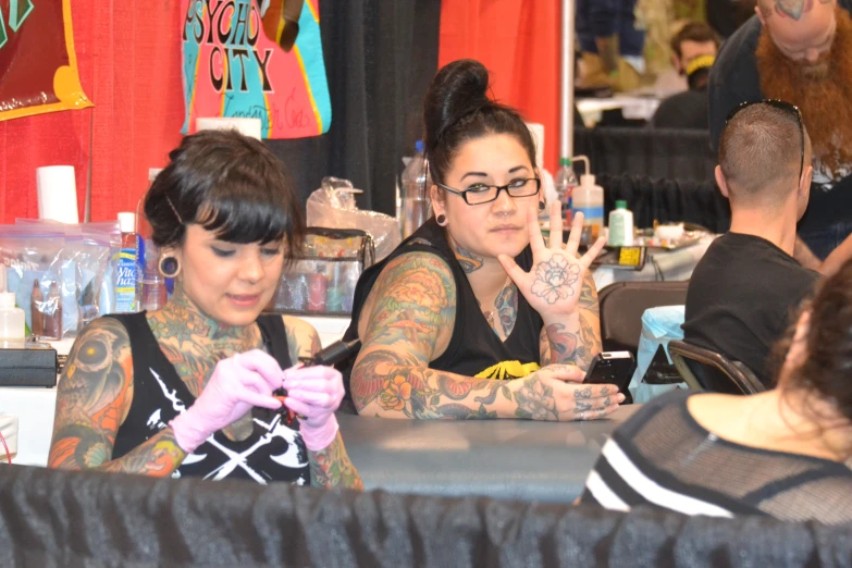 a couple of people sitting at a table with tattoos