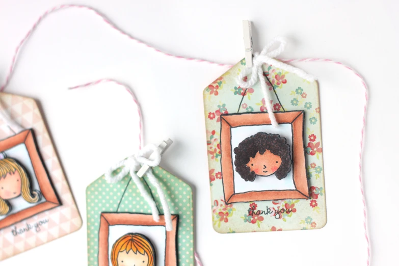 two tags hang from twine decorated with girls