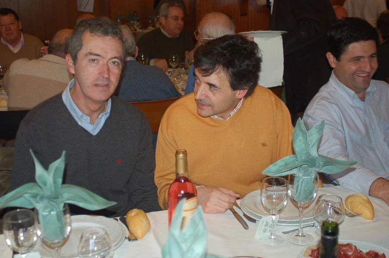 two men sit at a table with some bottles of wine