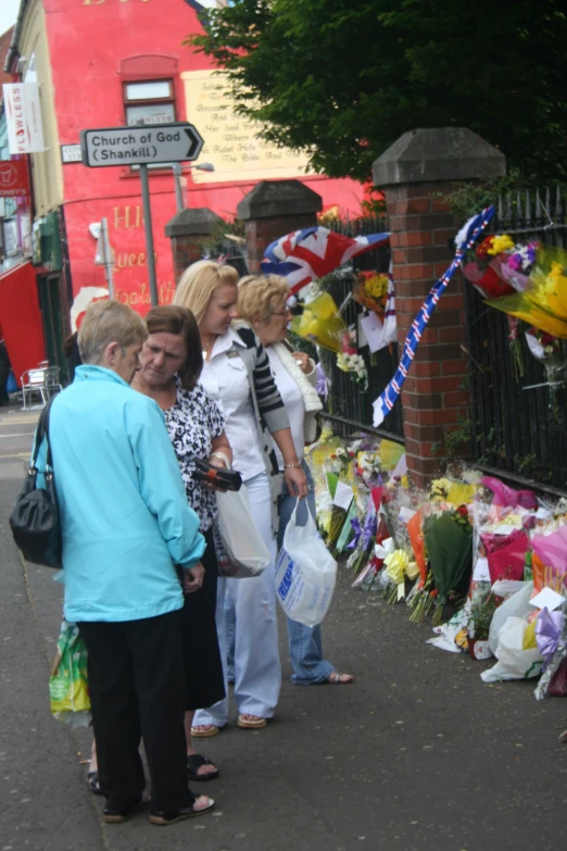 several women standing next to a fence with flowers