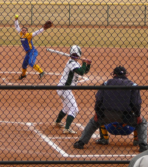 a pitcher throws a ball at a baseball game as a catcher prepares to catch it