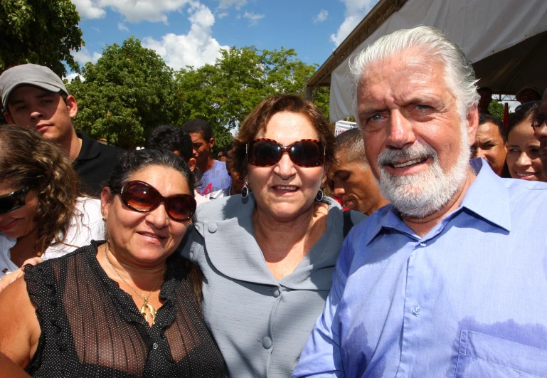 three people, one wearing glasses, pose together for a picture