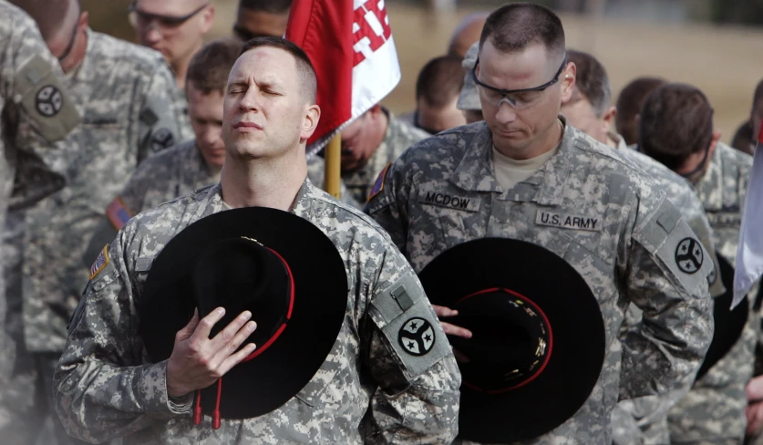 two soldiers stand while carrying hats