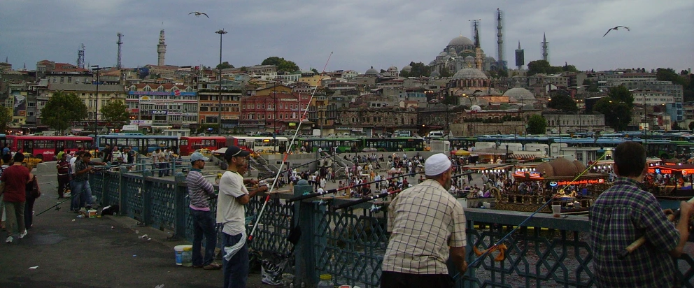 people walk along the bridge overlooking a crowded area