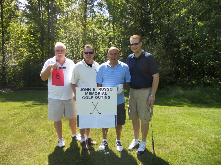 the four men are standing in front of a sign