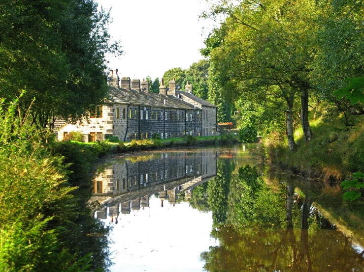 an old building sits on the bank of a river