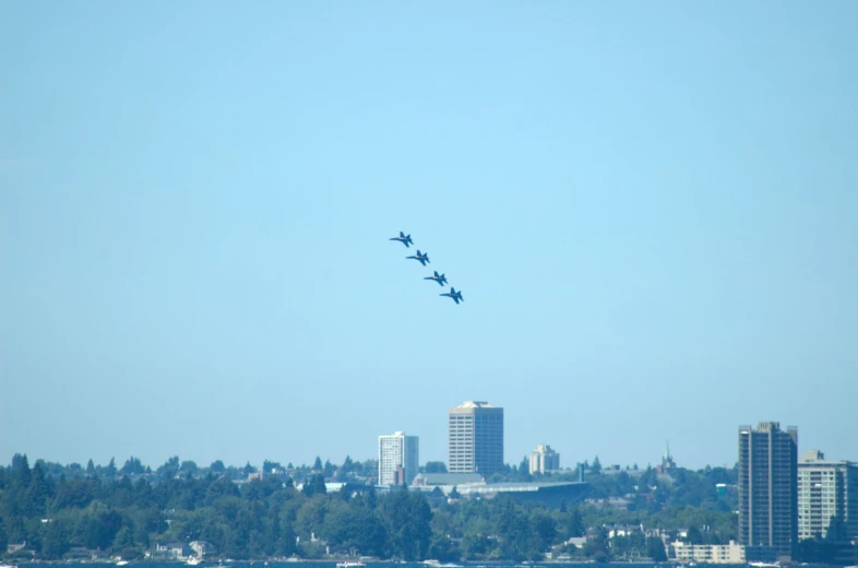 four airplanes fly over the city skyline from the water