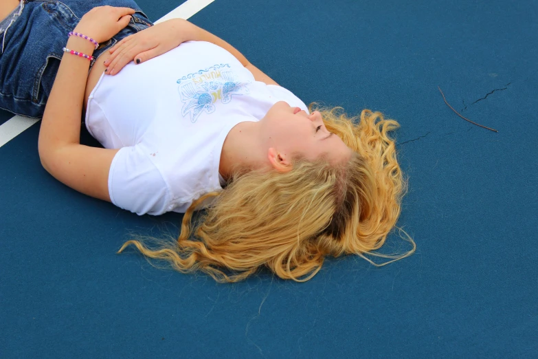 a beautiful woman laying on top of a tennis court