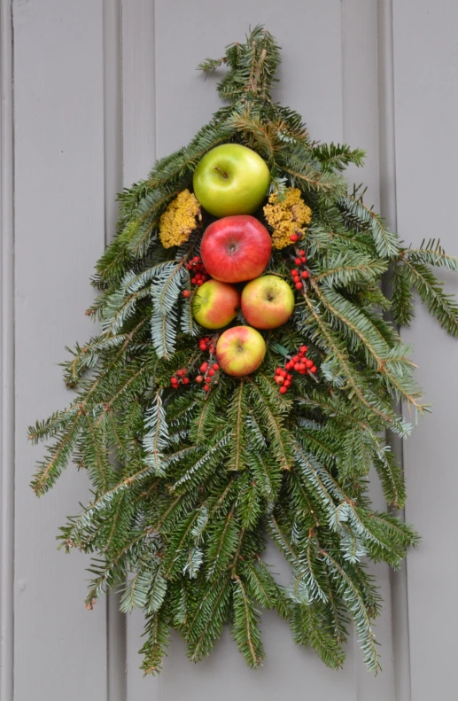 a christmas wreath made of pine, apple and pine cone with berries