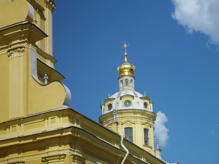 an ornate building with two towers has a gold spire and cross