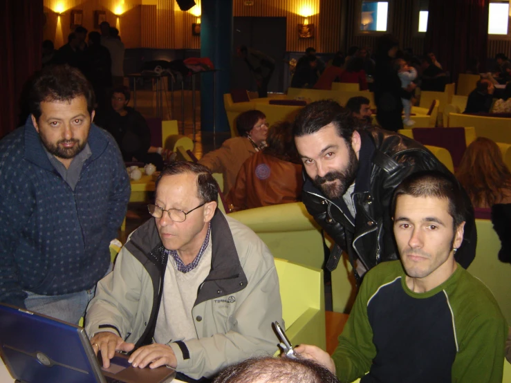 a couple of guys sitting next to each other with a laptop