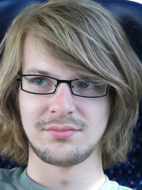 a man with long hair wearing glasses and a tie