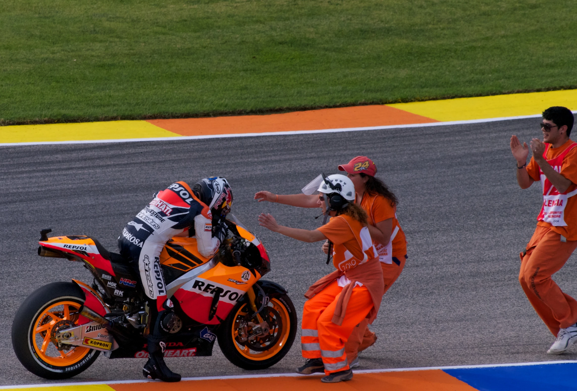 two motorcycle riders are next to an orange motorcycle