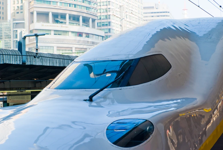 a white train with blue and yellow markings next to a bridge