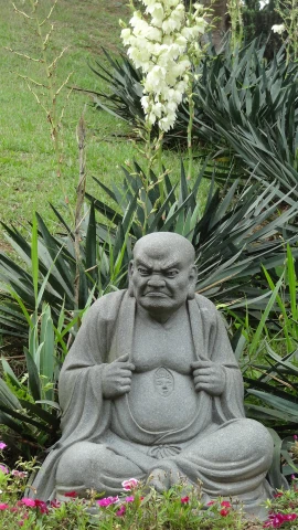 a large stone buddha statue sitting in a flower garden