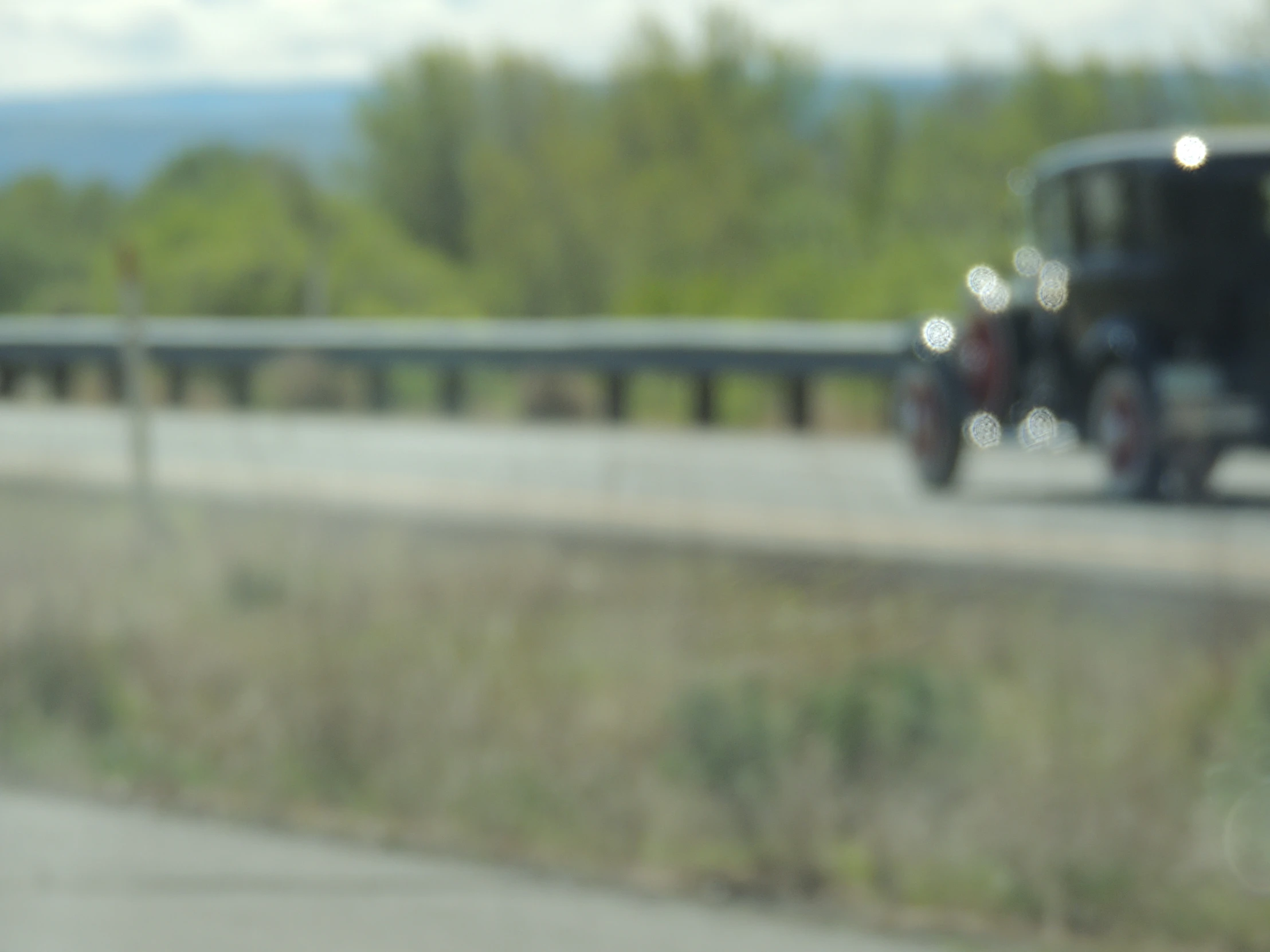 blurry view of the back of an old car driving on a highway