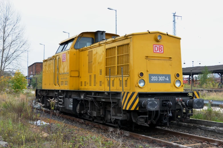 a yellow train sitting in a field next to a railroad track