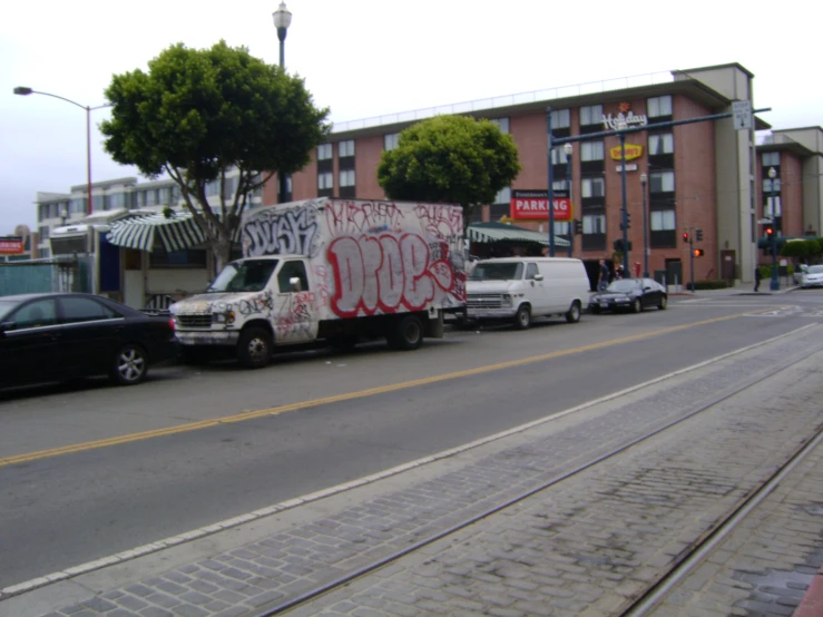 an empty street that has graffiti on it and parked cars