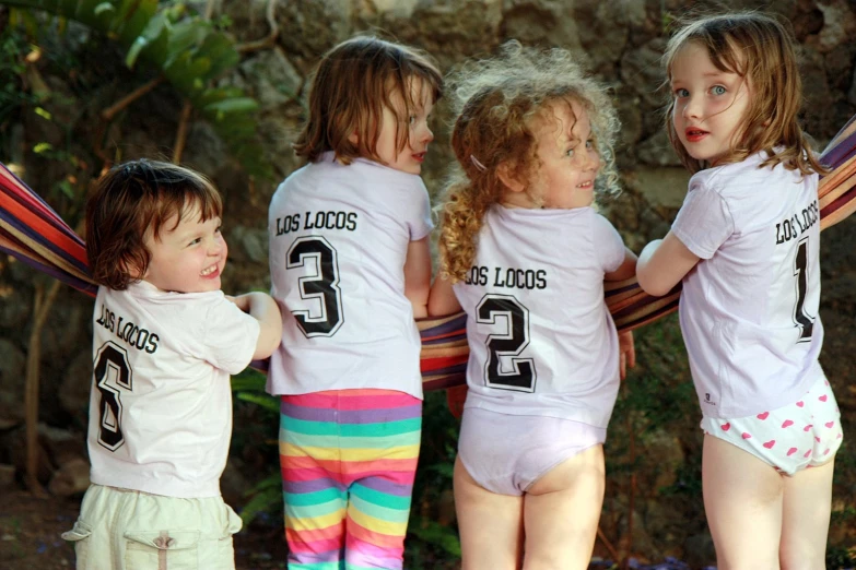 a group of little girls standing on top of a bench