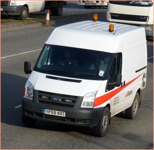 a white ford transit truck driving down the road