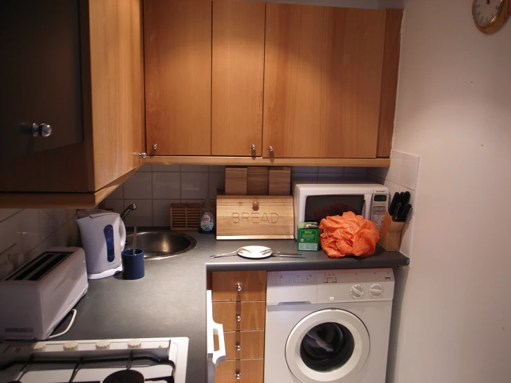 a kitchen area with washing machine, microwave and washer