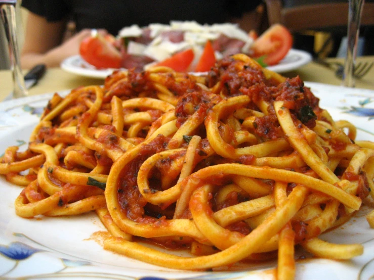 a plate of spaghetti topped with tomatoes and sauce
