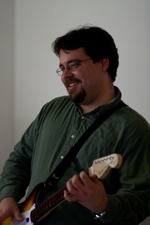 the man is playing his guitar in his room