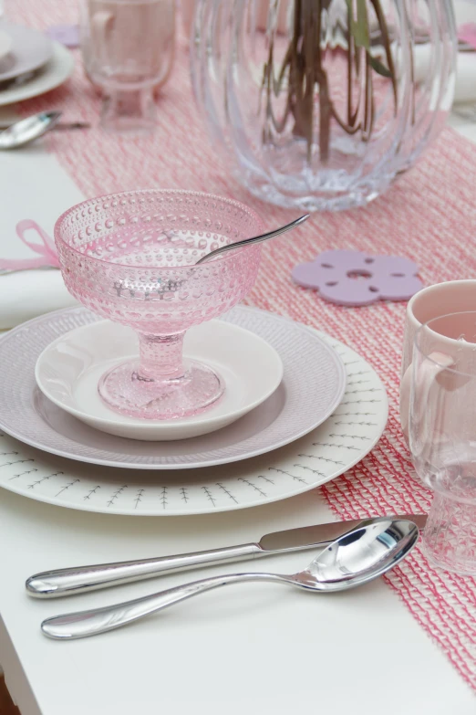 a white table set with pink napkins and pink dishes