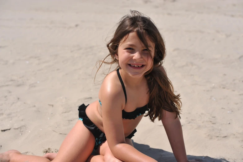 a little girl wearing a black bikini on the beach